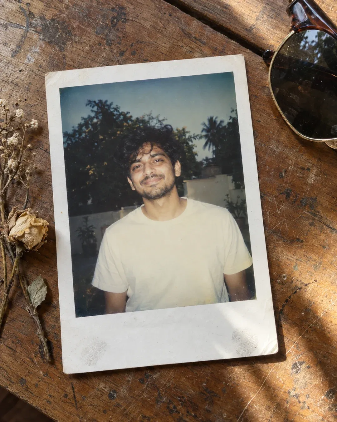 Example result: An instant-film print lies on a wooden table beside sunglasses, showing a smiling person lit by direct flash.